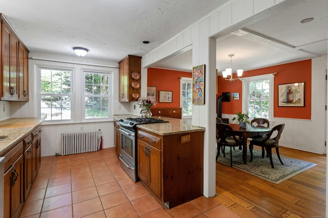 64 Old Kings Hwy S, Darien, CT 06820 - kitchen with radiator, stainless steel range with gas stovetop, brown cabinets, and a chandelier