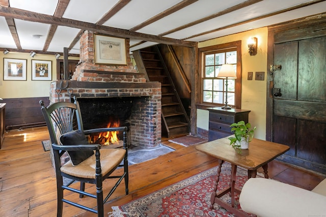 64 Old Kings Hwy S, Darien, CT 06820 - living area featuring hardwood / wood-style floors, stairs, beamed ceiling, wood walls, and a brick fireplace