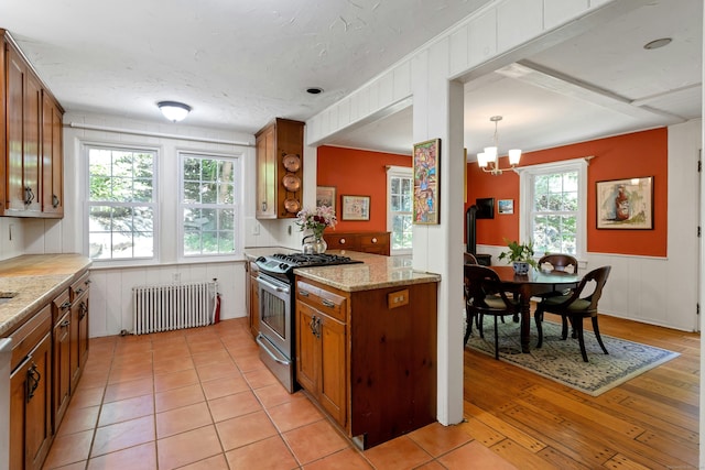 64 Old Kings Hwy S, Darien, CT 06820 - kitchen with radiator heating unit, stainless steel gas range oven, brown cabinetry, light wood-style floors, and a chandelier