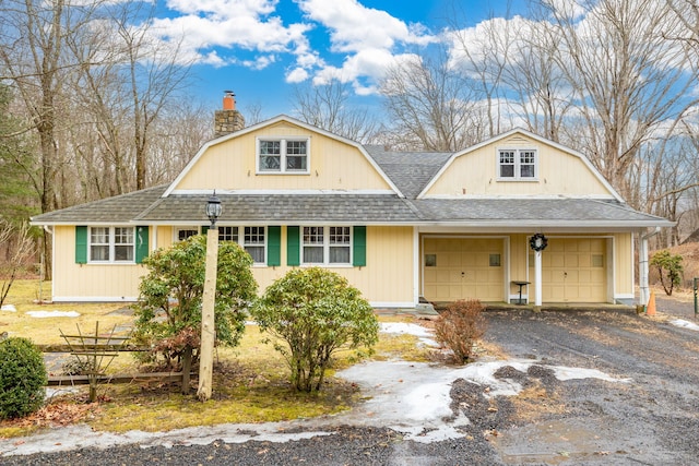 dutch colonial featuring a garage, a gambrel roof, roof with shingles, a chimney, and gravel driveway