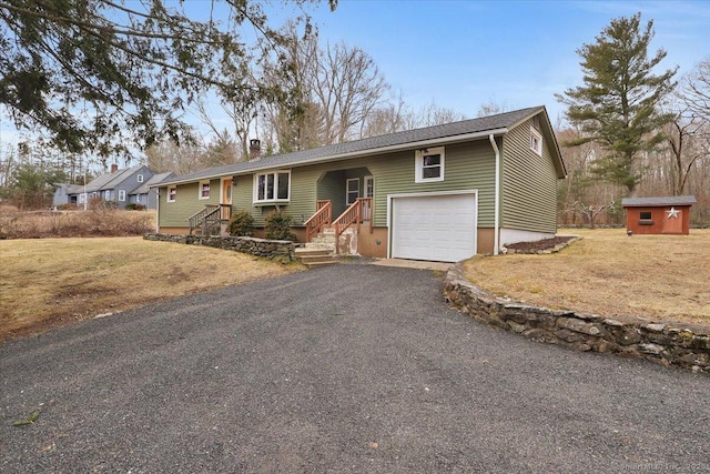 ranch-style house featuring an attached garage, driveway, an outdoor structure, and a front yard