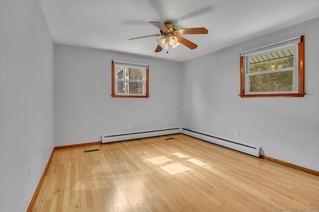 empty room featuring a baseboard radiator, plenty of natural light, baseboards, and wood finished floors