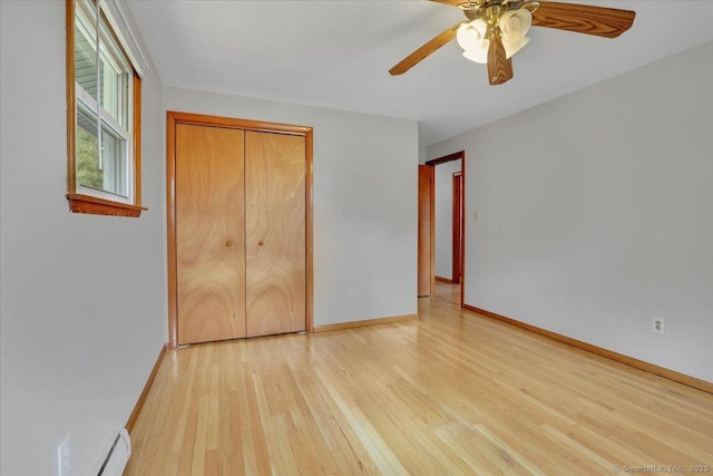 unfurnished bedroom featuring baseboards, a closet, a ceiling fan, and light wood-style floors