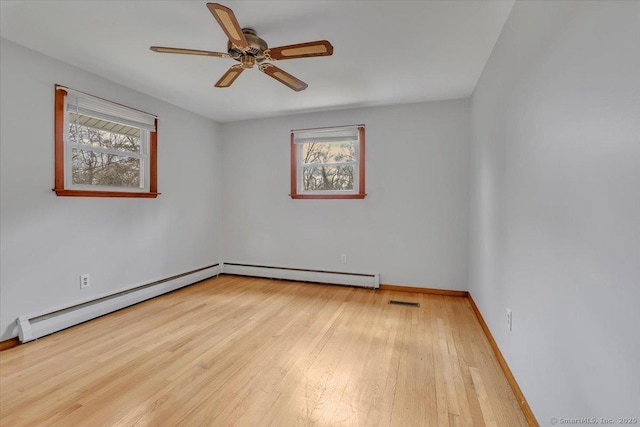 spare room with a healthy amount of sunlight, hardwood / wood-style floors, and baseboard heating