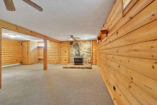 finished below grade area with carpet, a wood stove, ceiling fan, and a textured ceiling