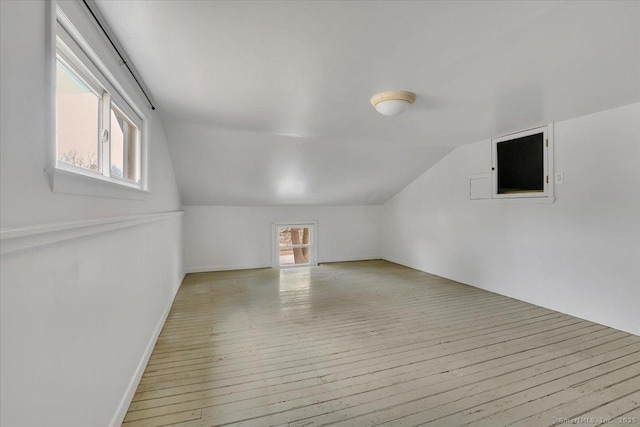 additional living space with a wealth of natural light, vaulted ceiling, and light wood finished floors