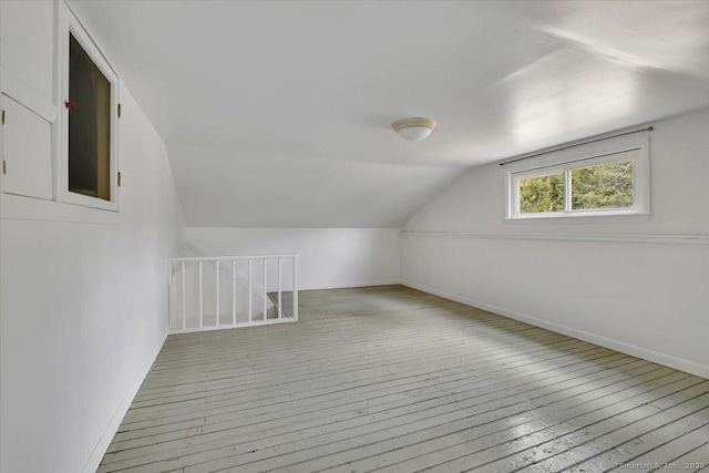 additional living space featuring vaulted ceiling, wood-type flooring, and baseboards