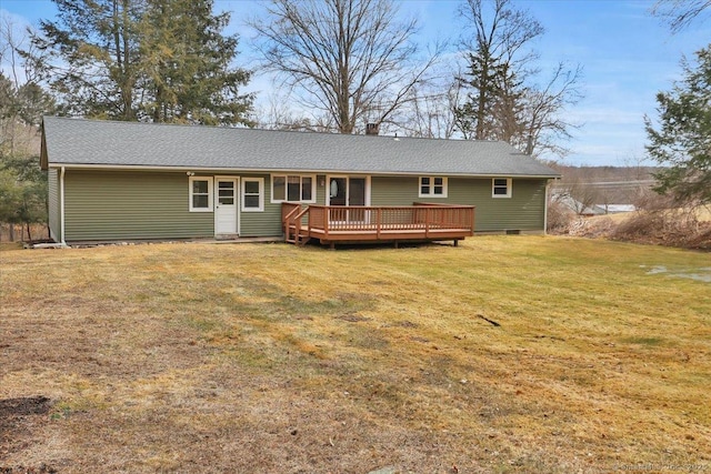 back of property with a chimney, roof with shingles, a lawn, and a deck