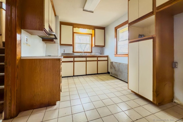 kitchen featuring light tile patterned floors, radiator heating unit, and a sink