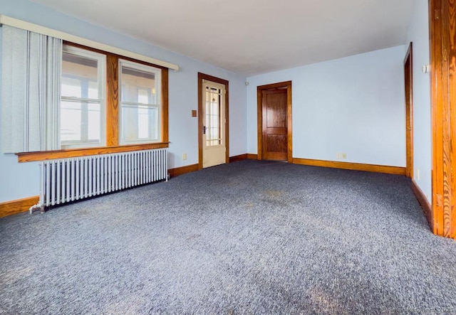 spare room featuring baseboards, carpet flooring, and radiator