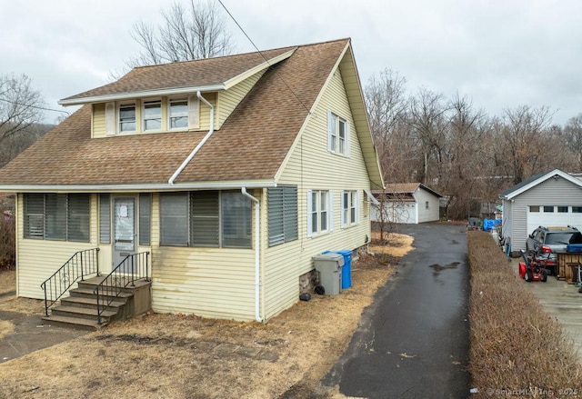 view of front of property featuring a garage, roof with shingles, and an outdoor structure