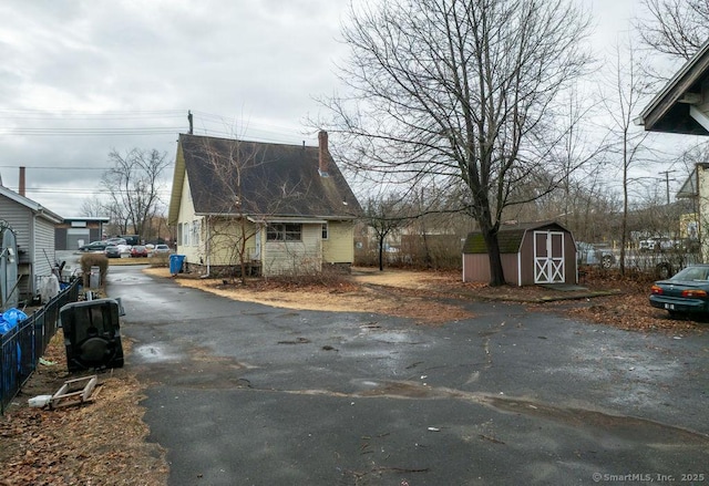 view of side of home featuring a storage shed, driveway, an outbuilding, and fence