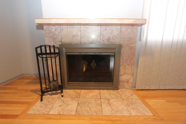 interior details with a tiled fireplace and wood finished floors