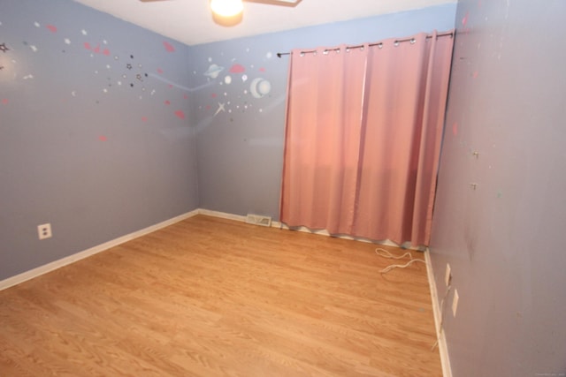 unfurnished room with light wood-style floors, baseboards, visible vents, and a ceiling fan