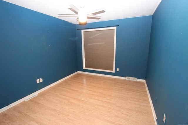 unfurnished room featuring baseboards, wood finished floors, visible vents, and a ceiling fan