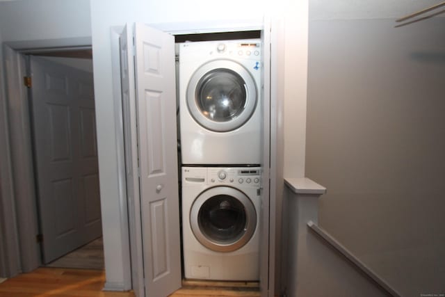 clothes washing area with laundry area, light wood-style flooring, and stacked washer and clothes dryer