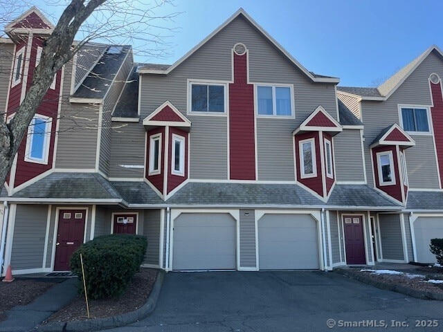 multi unit property featuring a garage, driveway, and a shingled roof