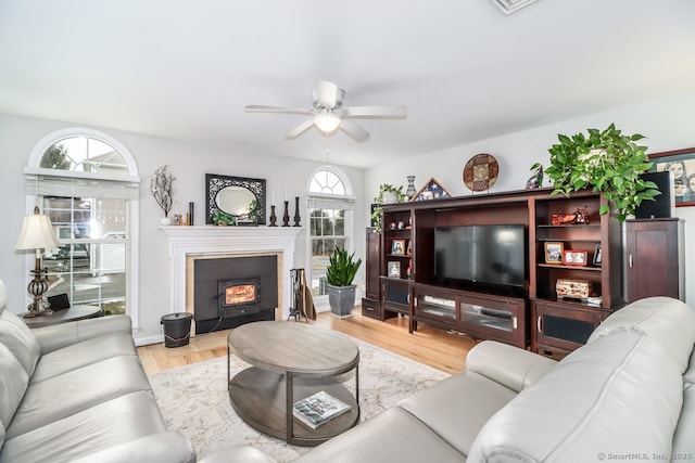 living area with baseboards, light wood-style flooring, a wealth of natural light, and a ceiling fan