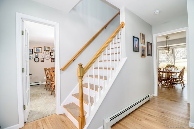 staircase with a baseboard heating unit, wood finished floors, baseboards, baseboard heating, and an inviting chandelier