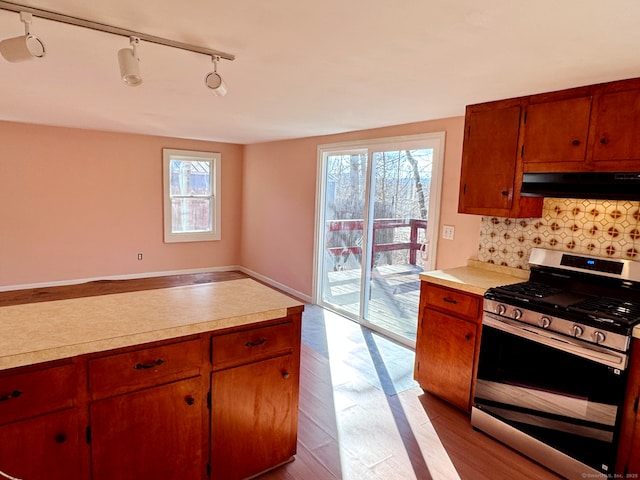 kitchen featuring stainless steel gas stove, tasteful backsplash, extractor fan, and a wealth of natural light