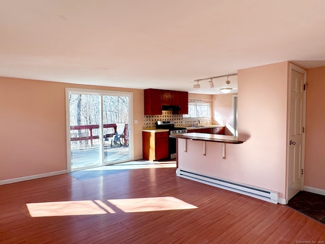 kitchen with a baseboard heating unit, stainless steel electric range oven, decorative backsplash, and wood finished floors