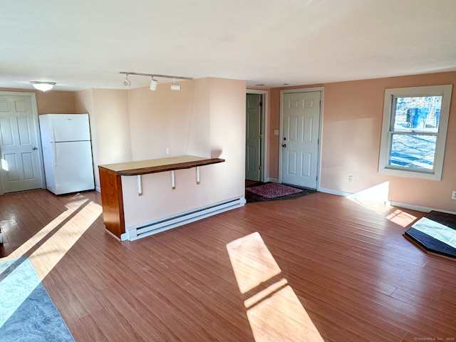 kitchen with baseboards, a baseboard radiator, wood finished floors, freestanding refrigerator, and rail lighting