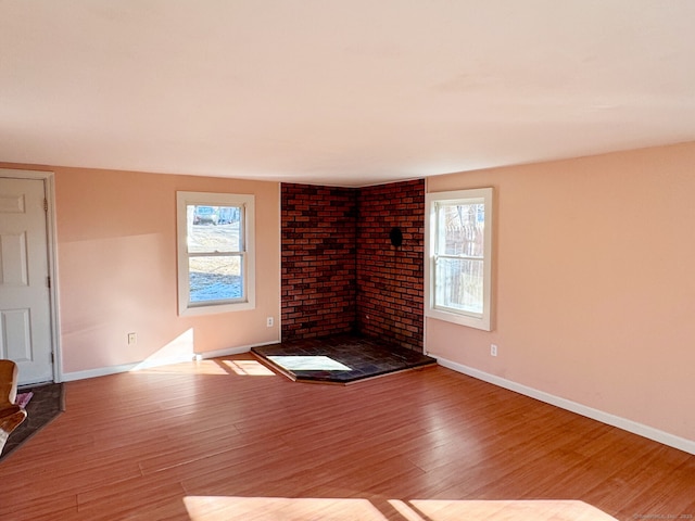 unfurnished living room featuring a fireplace, wood finished floors, and baseboards