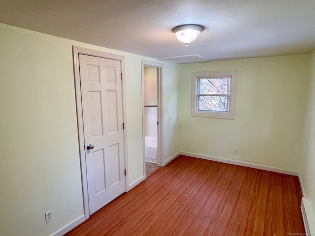 unfurnished bedroom featuring a baseboard radiator, baseboards, and wood finished floors