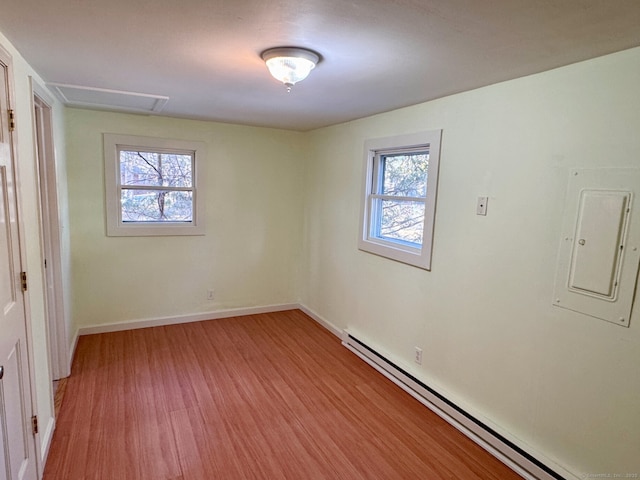 unfurnished bedroom with light wood-type flooring, electric panel, baseboard heating, and multiple windows