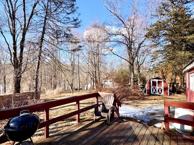 wooden terrace with a storage shed, an outbuilding, and a grill