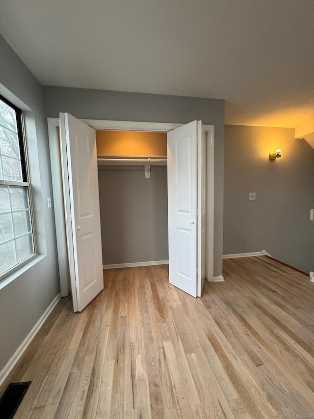 unfurnished bedroom with light wood finished floors, visible vents, and baseboards