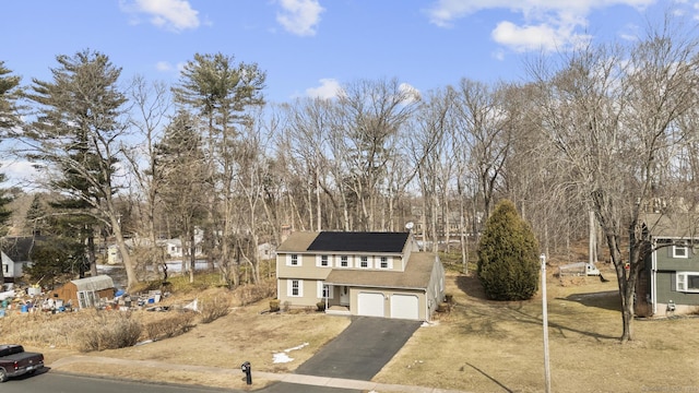 colonial home featuring driveway, a garage, and solar panels