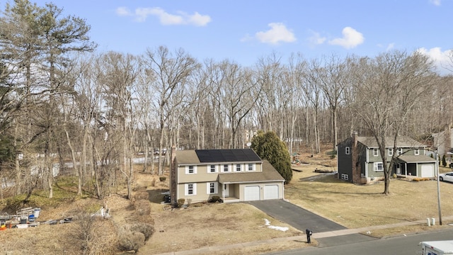 colonial home featuring solar panels, a front lawn, and driveway