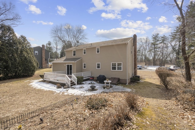 rear view of property featuring a patio, a chimney, and a wooden deck