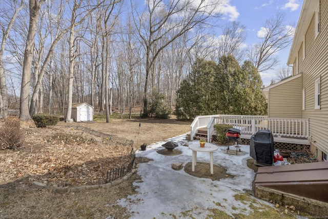 view of yard featuring a patio area, an outdoor structure, a wooden deck, and a storage unit