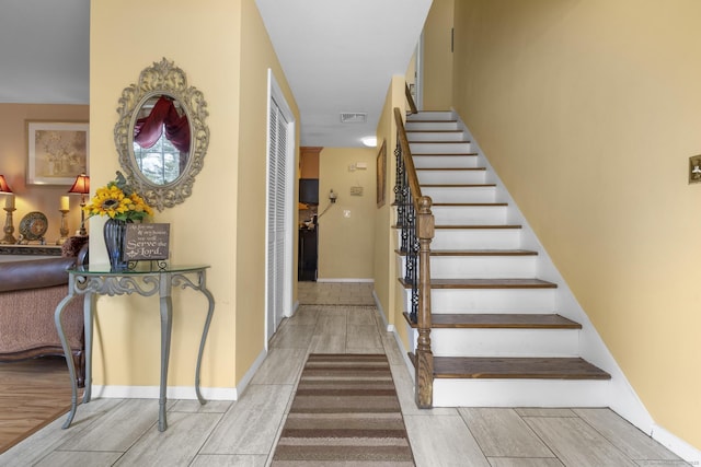 stairs featuring wood tiled floor, visible vents, and baseboards