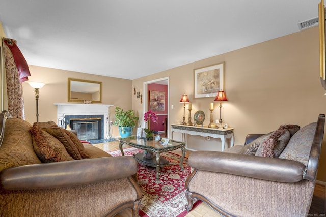 living area featuring a fireplace with flush hearth, visible vents, and baseboards