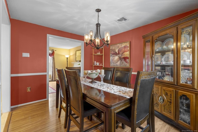 dining area with visible vents, a notable chandelier, light wood-style flooring, and baseboards