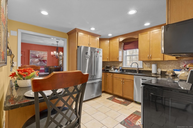 kitchen with a notable chandelier, stainless steel appliances, dark countertops, tasteful backsplash, and a sink