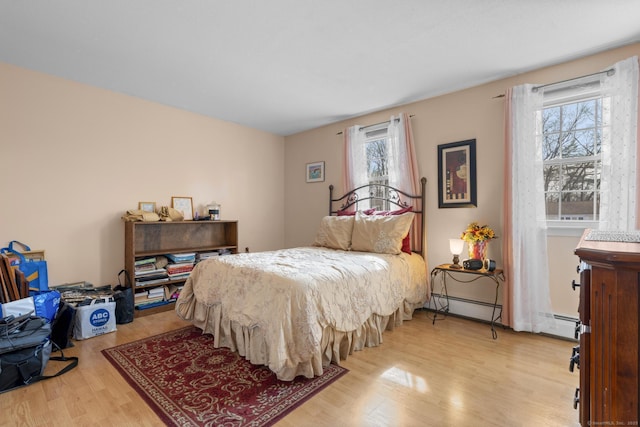 bedroom with light wood-style floors and a baseboard heating unit