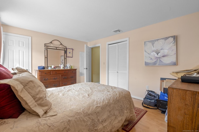 bedroom with light wood-style flooring, a closet, visible vents, and baseboards