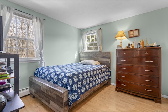 bedroom featuring baseboard heating, light wood-style flooring, and baseboards