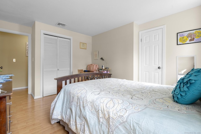 bedroom with light wood-style floors, baseboards, visible vents, and a closet