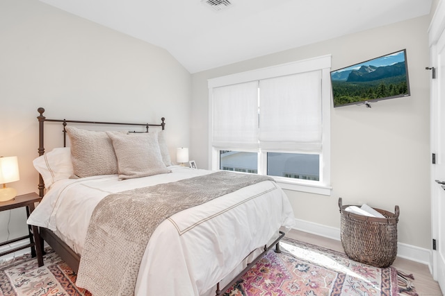 bedroom with visible vents, baseboards, vaulted ceiling, and wood finished floors