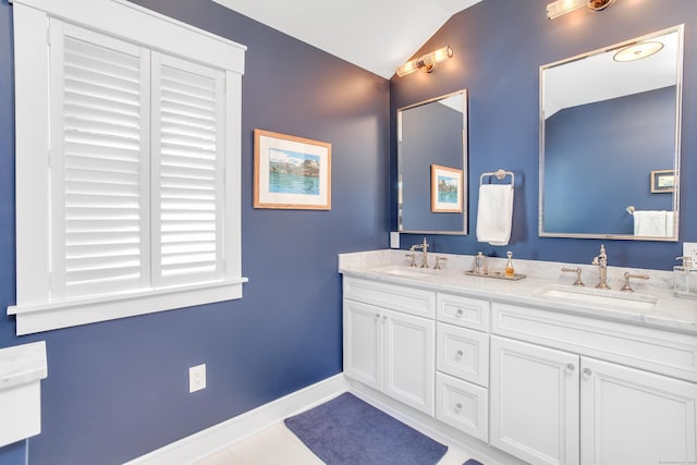 bathroom featuring vaulted ceiling, a sink, baseboards, and double vanity