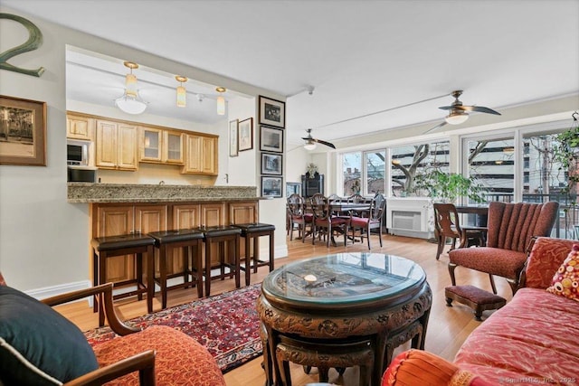 living room featuring ceiling fan, light wood-type flooring, and baseboards