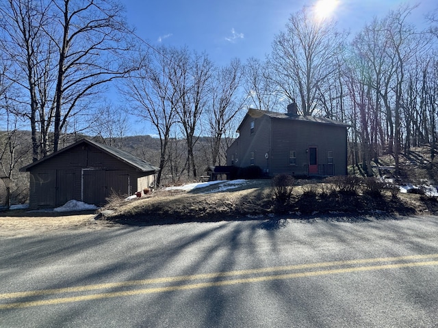 view of side of home with an outbuilding, a chimney, and an outdoor structure