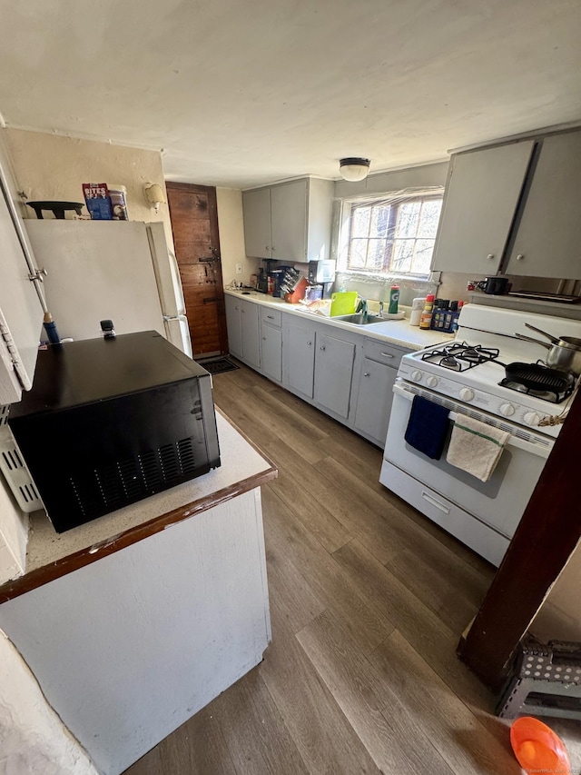 kitchen featuring white gas stove, gray cabinets, light countertops, wood finished floors, and black microwave