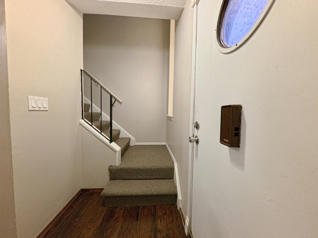 staircase featuring wood finished floors and baseboards