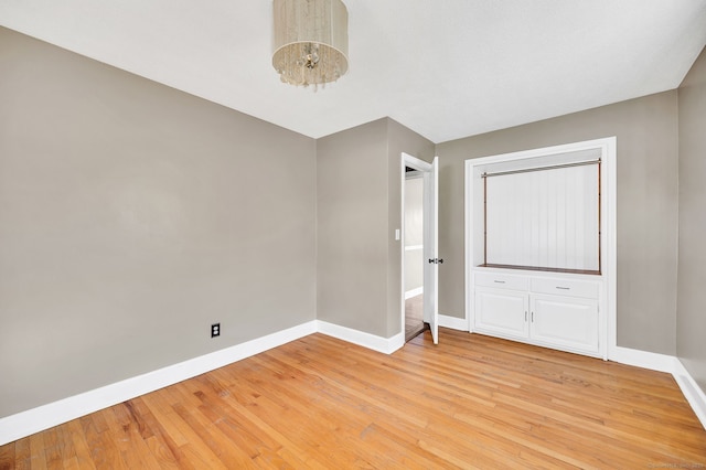 interior space with a chandelier, light wood-type flooring, and baseboards